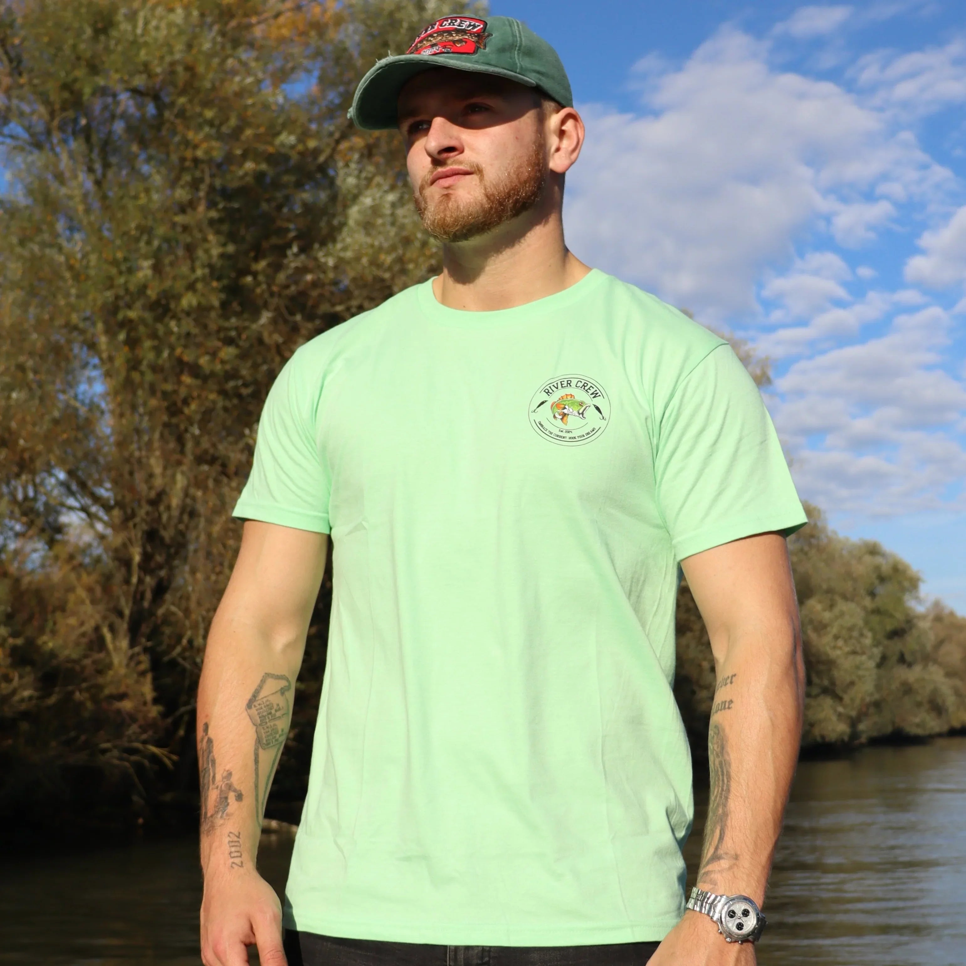 Groen River Crew Perch T-shirt met perch-vislogo en vispluggen, perfect voor avontuurlijke vissers.