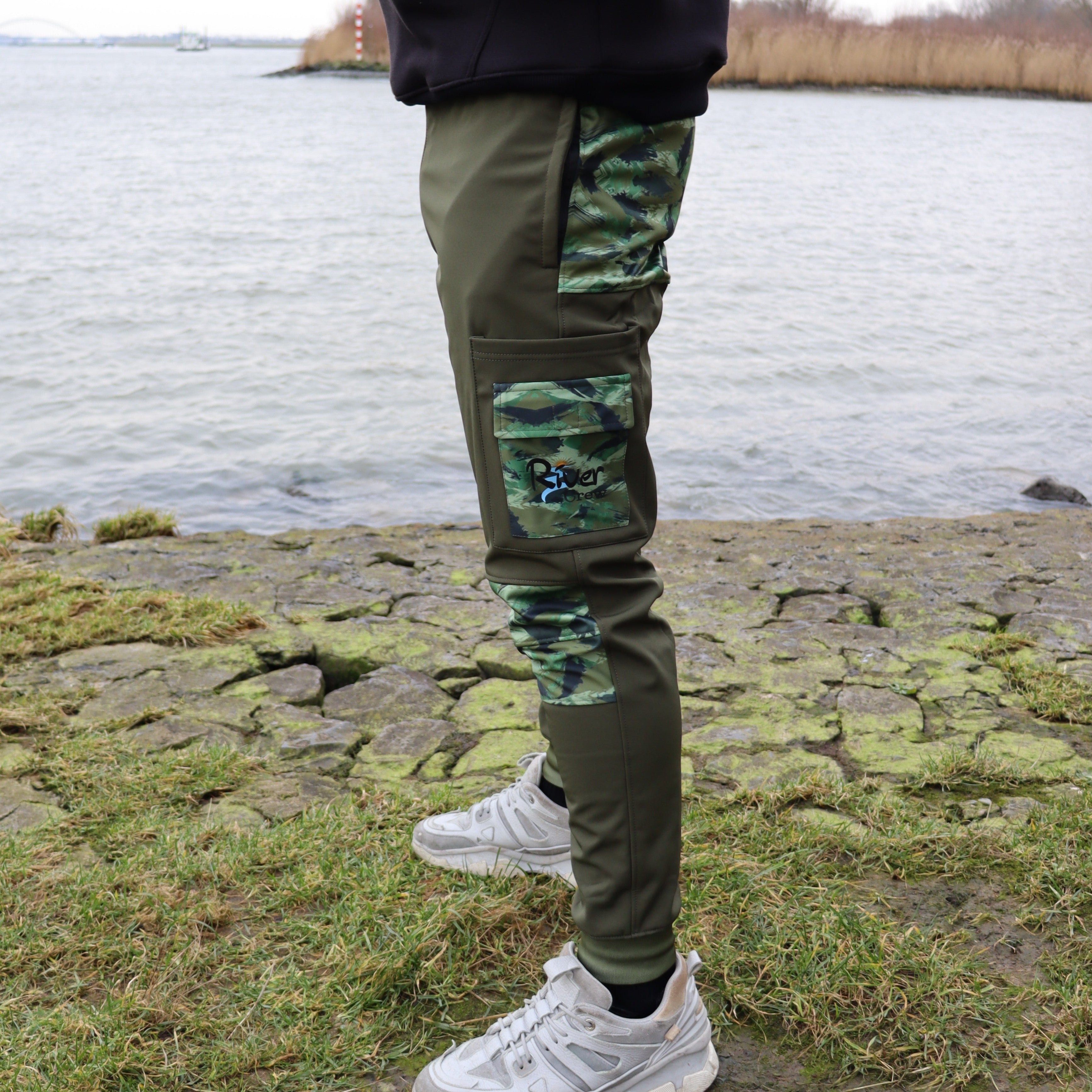 Linkerzijde van de River Crew Softshell Adventure Trousers, voorzien van functionele zakken en duurzame stof voor ruige omstandigheden.