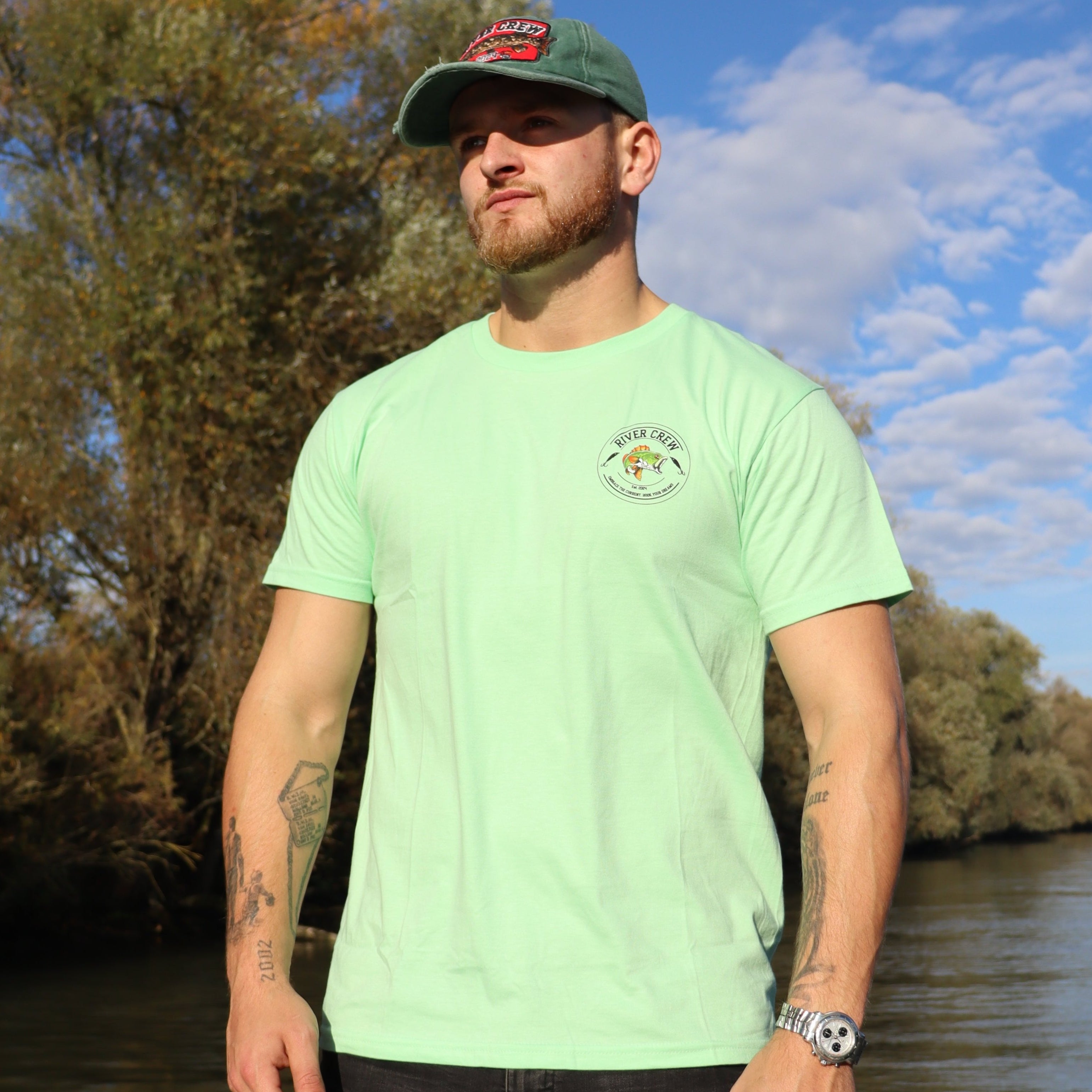 Groen River Crew Perch T-shirt met perch-vislogo en vispluggen, perfect voor avontuurlijke vissers.