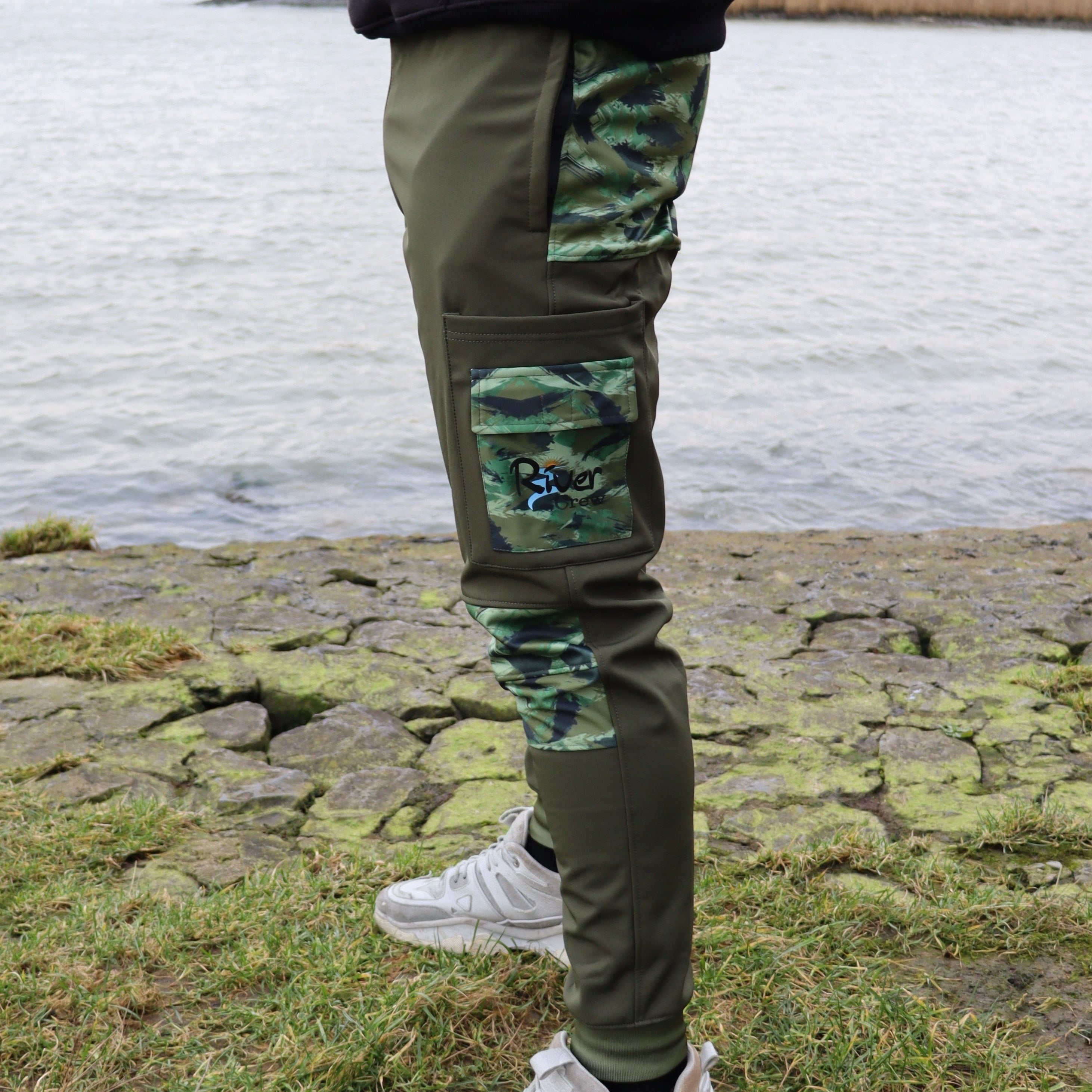 Linkerzijde van de River Crew Softshell Adventure Trousers, voorzien van functionele zakken en duurzame stof voor ruige omstandigheden.